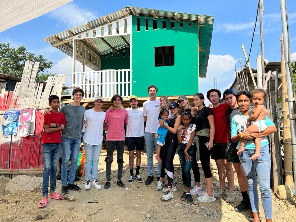 Alejandro with fellow volunteers and a family in front of the finished house built by 10 KAZAS